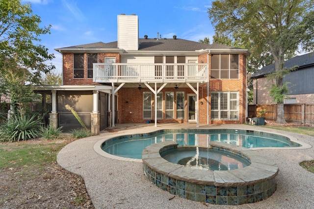 back of property featuring a patio, a chimney, fence, a pool with connected hot tub, and brick siding