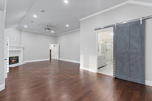 unfurnished living room featuring ceiling fan, lofted ceiling, a barn door, wood finished floors, and visible vents