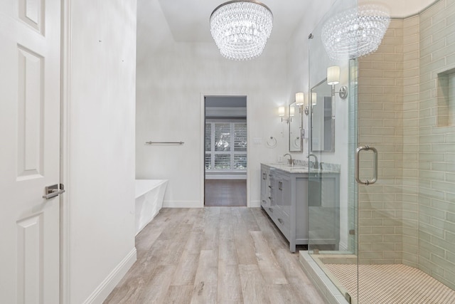 bathroom featuring a chandelier, wood finished floors, a shower stall, and vanity