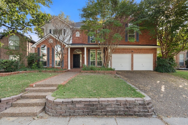 traditional-style house with gravel driveway, a front yard, a garage, and brick siding