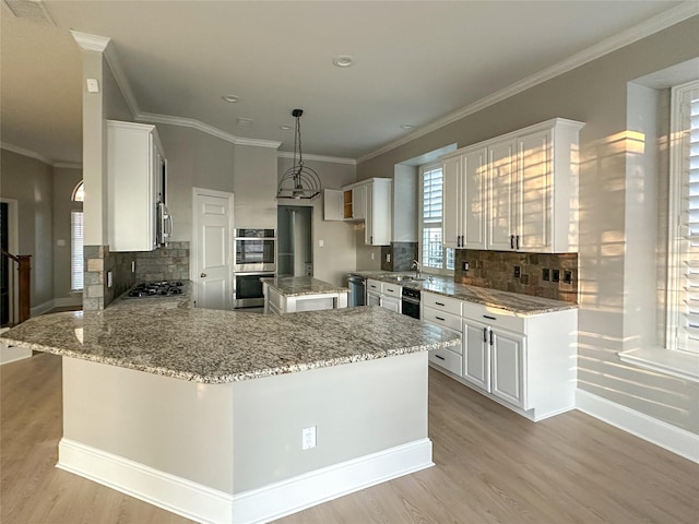 kitchen featuring kitchen peninsula, pendant lighting, appliances with stainless steel finishes, white cabinets, and a kitchen island