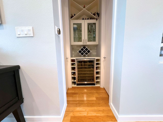 wine room with light hardwood / wood-style floors and beverage cooler