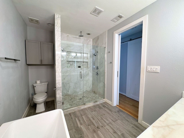 bathroom featuring wood-type flooring, a shower with door, and toilet