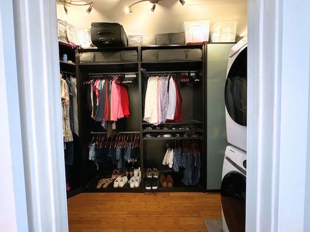 walk in closet featuring hardwood / wood-style flooring and stacked washing maching and dryer