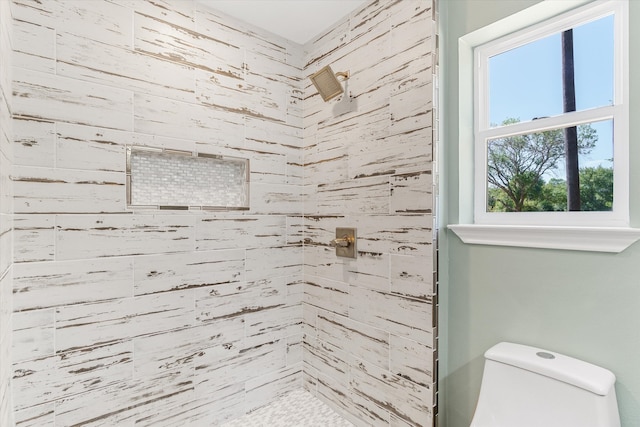 bathroom featuring a tile shower and toilet