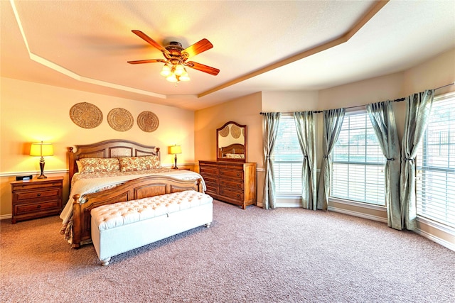 carpeted bedroom featuring ceiling fan, a raised ceiling, and a textured ceiling