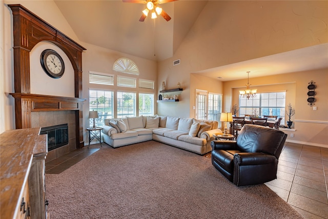 tiled living room featuring a tiled fireplace, ceiling fan with notable chandelier, and high vaulted ceiling