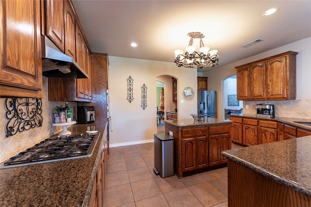 kitchen with backsplash, appliances with stainless steel finishes, decorative light fixtures, light tile patterned flooring, and a chandelier