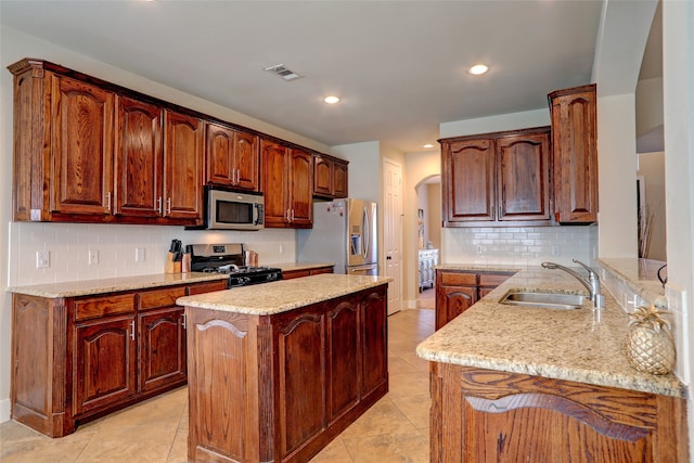 kitchen with light stone counters, sink, kitchen peninsula, stainless steel appliances, and decorative backsplash