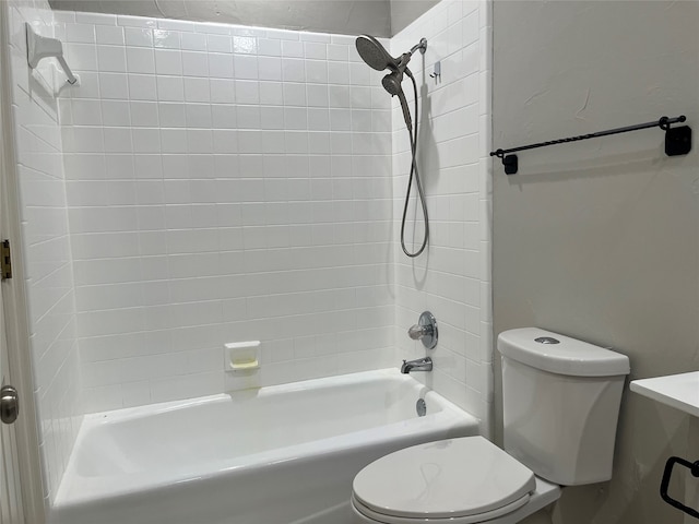 bathroom featuring toilet and tiled shower / bath