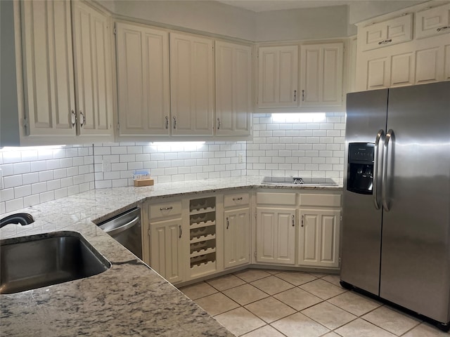 kitchen featuring light stone countertops, backsplash, appliances with stainless steel finishes, and sink