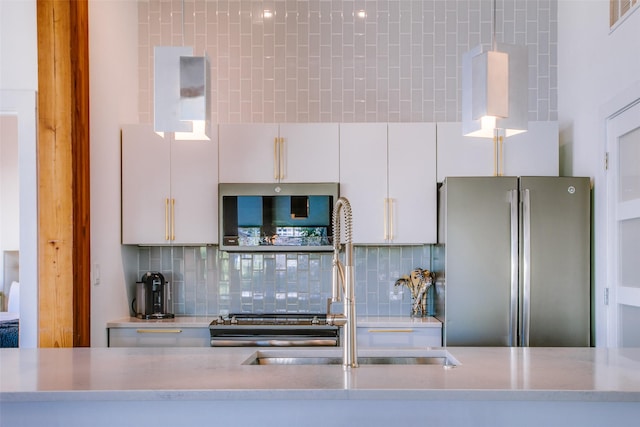 kitchen with tasteful backsplash, stainless steel refrigerator, white cabinetry, and sink