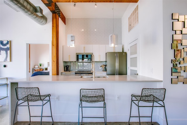 kitchen with sink, stainless steel appliances, decorative light fixtures, decorative backsplash, and white cabinets