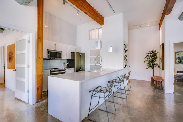 kitchen with appliances with stainless steel finishes, backsplash, beam ceiling, decorative light fixtures, and white cabinets