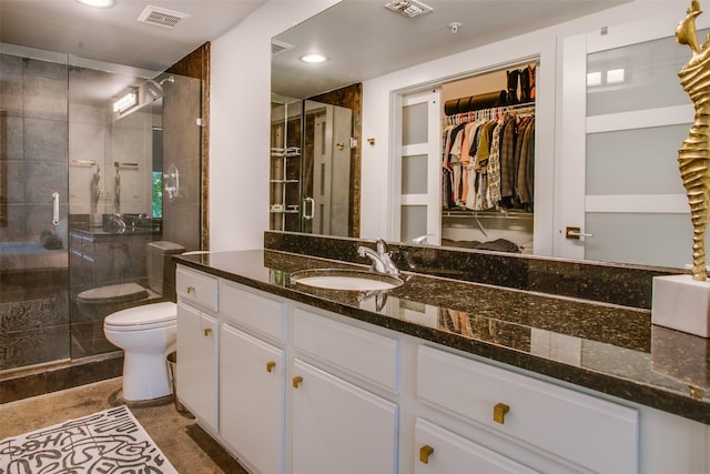 bathroom with a shower with door, vanity, and toilet