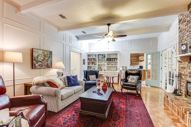 living room featuring ceiling fan, a textured ceiling, parquet flooring, and beam ceiling