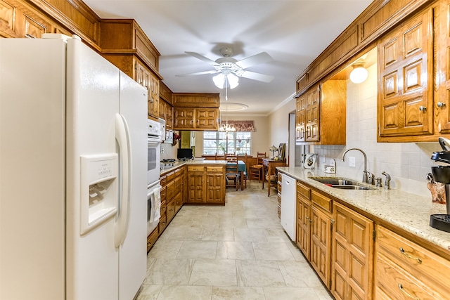 kitchen with tasteful backsplash, white appliances, ceiling fan with notable chandelier, sink, and light stone countertops