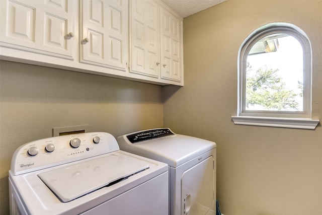 washroom with a textured ceiling, washer and clothes dryer, and cabinets