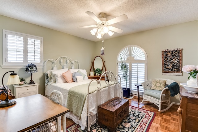 bedroom with ceiling fan, a textured ceiling, and parquet flooring