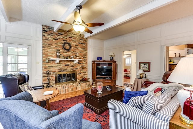 living room with ceiling fan, beamed ceiling, a wealth of natural light, and a textured ceiling