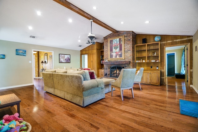 living room featuring a brick fireplace, wooden walls, lofted ceiling with beams, and hardwood / wood-style floors