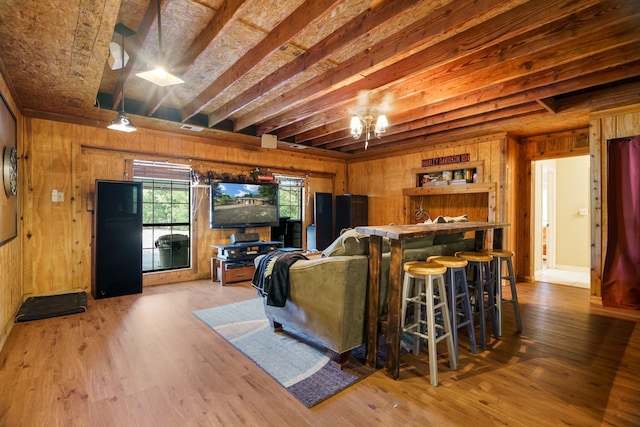 living room with hardwood / wood-style flooring, wood walls, beam ceiling, and indoor bar