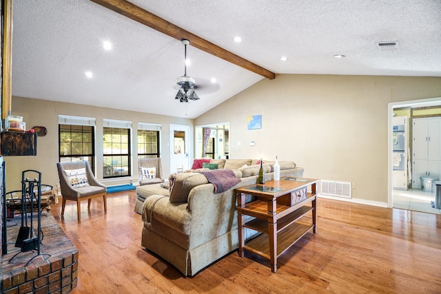 living room featuring ceiling fan, vaulted ceiling with beams, a textured ceiling, and light hardwood / wood-style floors