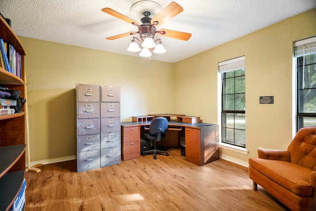 office space with a textured ceiling, ceiling fan, light wood-type flooring, and a healthy amount of sunlight