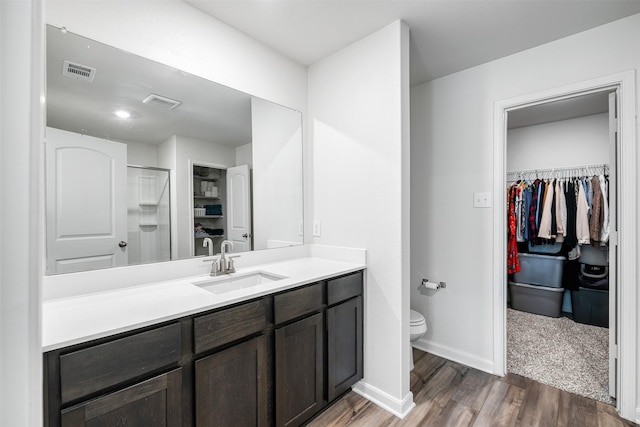 bathroom with walk in shower, vanity, toilet, and hardwood / wood-style floors