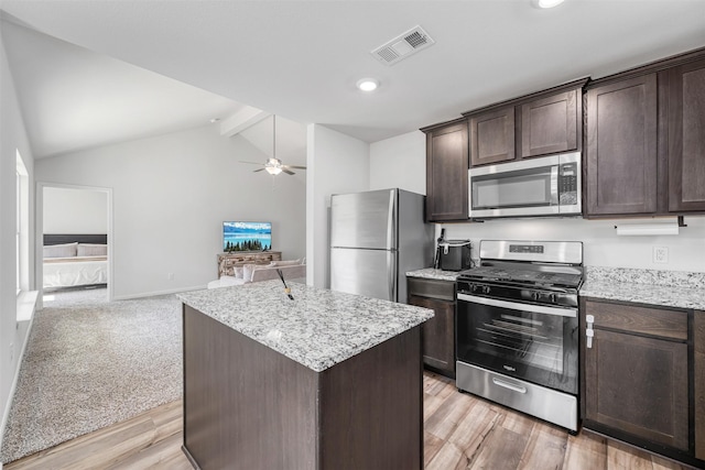 kitchen with appliances with stainless steel finishes, an island with sink, vaulted ceiling with beams, ceiling fan, and light hardwood / wood-style floors