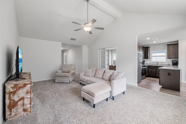 living room featuring sink, ceiling fan, beam ceiling, high vaulted ceiling, and light carpet