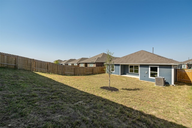 rear view of property featuring central AC and a lawn