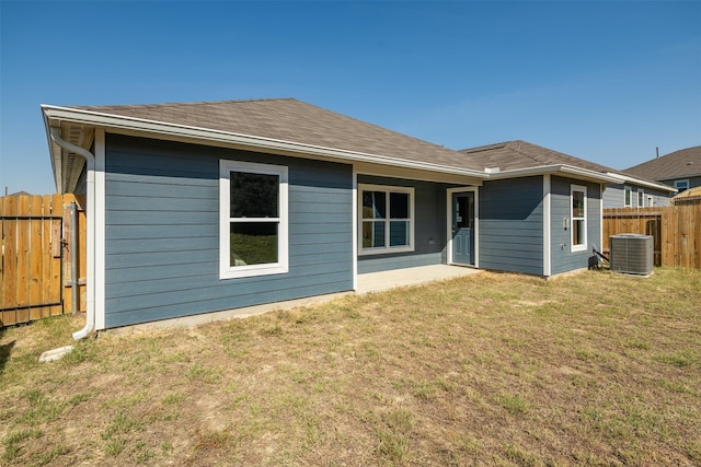 back of house featuring central AC unit and a lawn