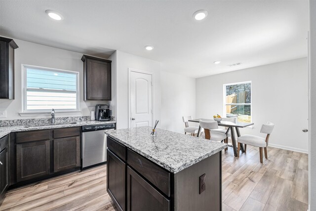 kitchen with sink, light wood-type flooring, stainless steel dishwasher, and a kitchen island