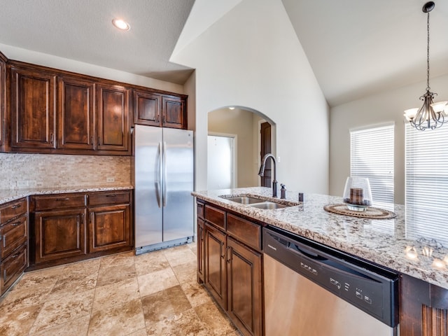 kitchen with sink, hanging light fixtures, stainless steel appliances, light stone counters, and a chandelier