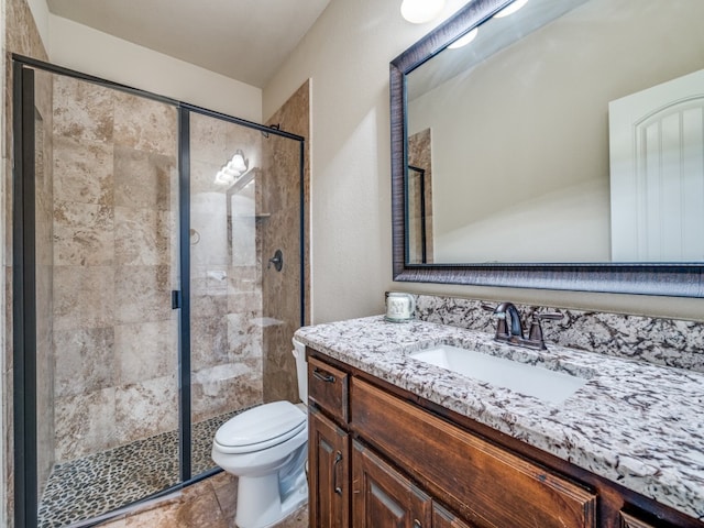 bathroom featuring vanity, toilet, and a shower with shower door