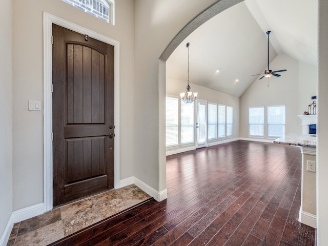 entrance foyer featuring ceiling fan with notable chandelier, high vaulted ceiling, and dark hardwood / wood-style floors