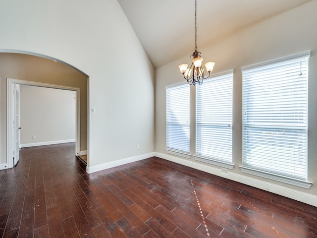 empty room featuring high vaulted ceiling, a healthy amount of sunlight, dark hardwood / wood-style flooring, and a chandelier