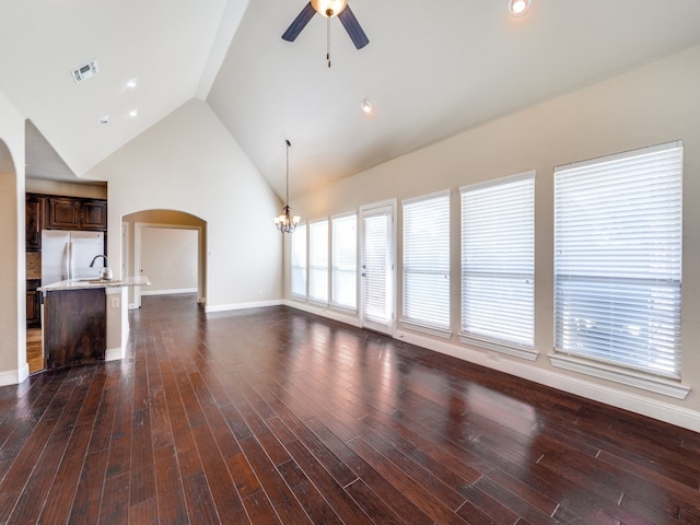 unfurnished living room featuring dark wood-type flooring, high vaulted ceiling, sink, and ceiling fan with notable chandelier