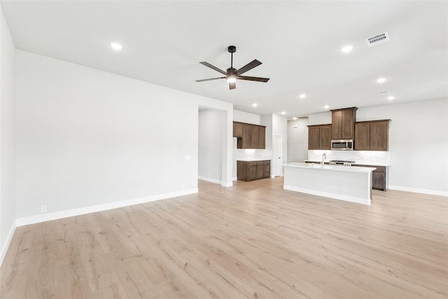 unfurnished living room with ceiling fan, light hardwood / wood-style floors, and sink