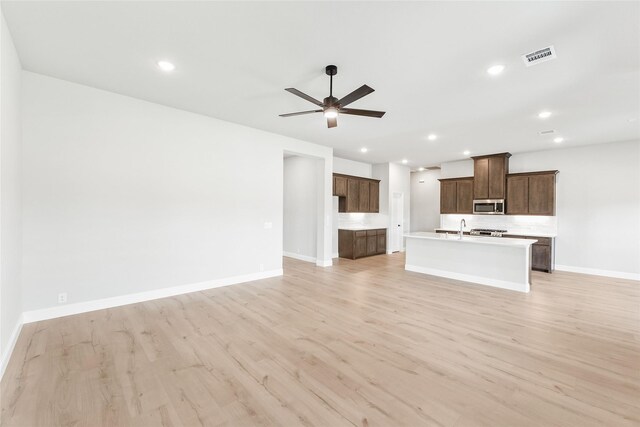 unfurnished living room with sink, ceiling fan, and light wood-type flooring