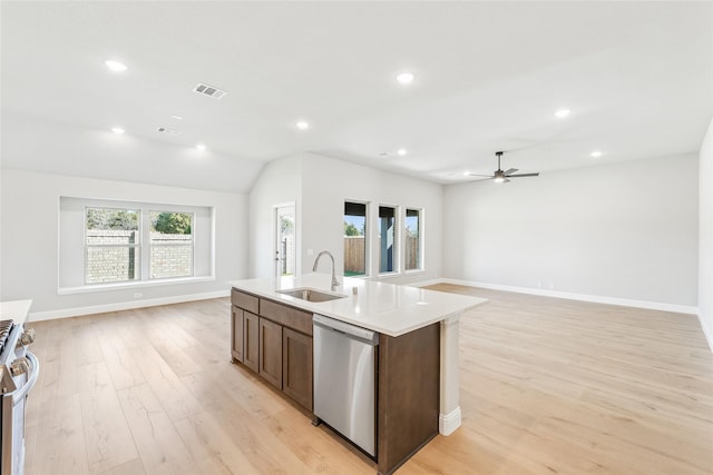 kitchen featuring appliances with stainless steel finishes, an island with sink, ceiling fan, sink, and light hardwood / wood-style flooring