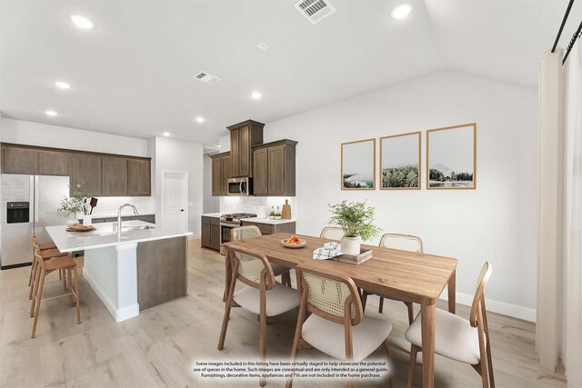 kitchen with dark brown cabinetry, sink, light hardwood / wood-style flooring, appliances with stainless steel finishes, and a kitchen island with sink