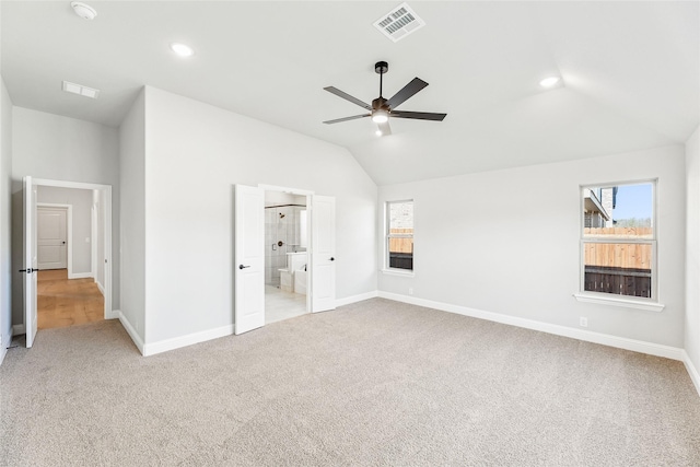 unfurnished bedroom with multiple windows, light carpet, connected bathroom, and ceiling fan