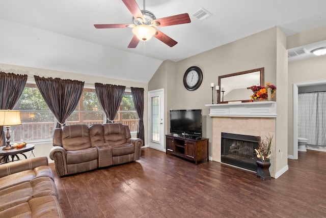 living room featuring dark wood-type flooring, ceiling fan, vaulted ceiling, and a tiled fireplace