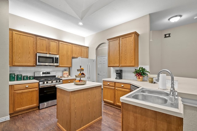 kitchen with sink, tasteful backsplash, a kitchen island, appliances with stainless steel finishes, and dark hardwood / wood-style flooring