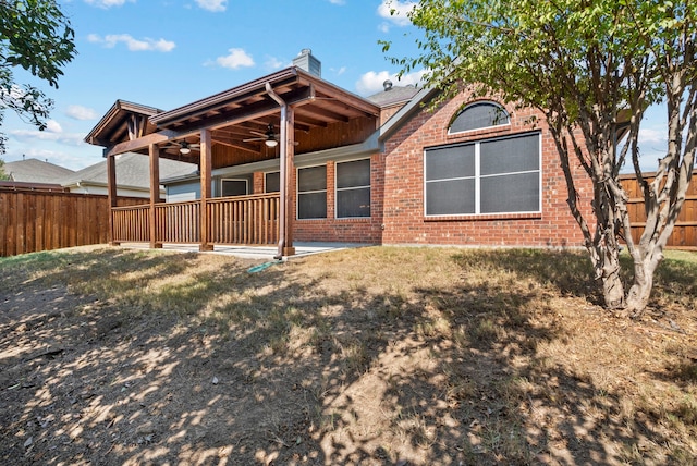 rear view of property featuring a yard and ceiling fan