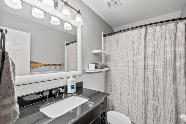 bathroom with curtained shower, vanity, and toilet