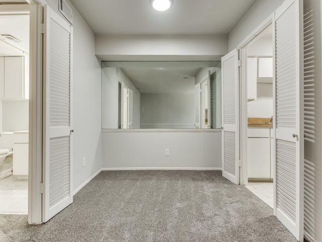 unfurnished bedroom with ensuite bathroom and light colored carpet