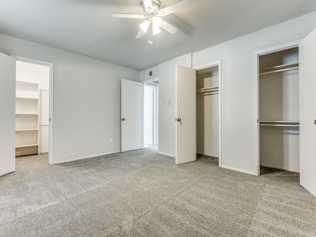 unfurnished bedroom with light carpet, multiple closets, and ceiling fan